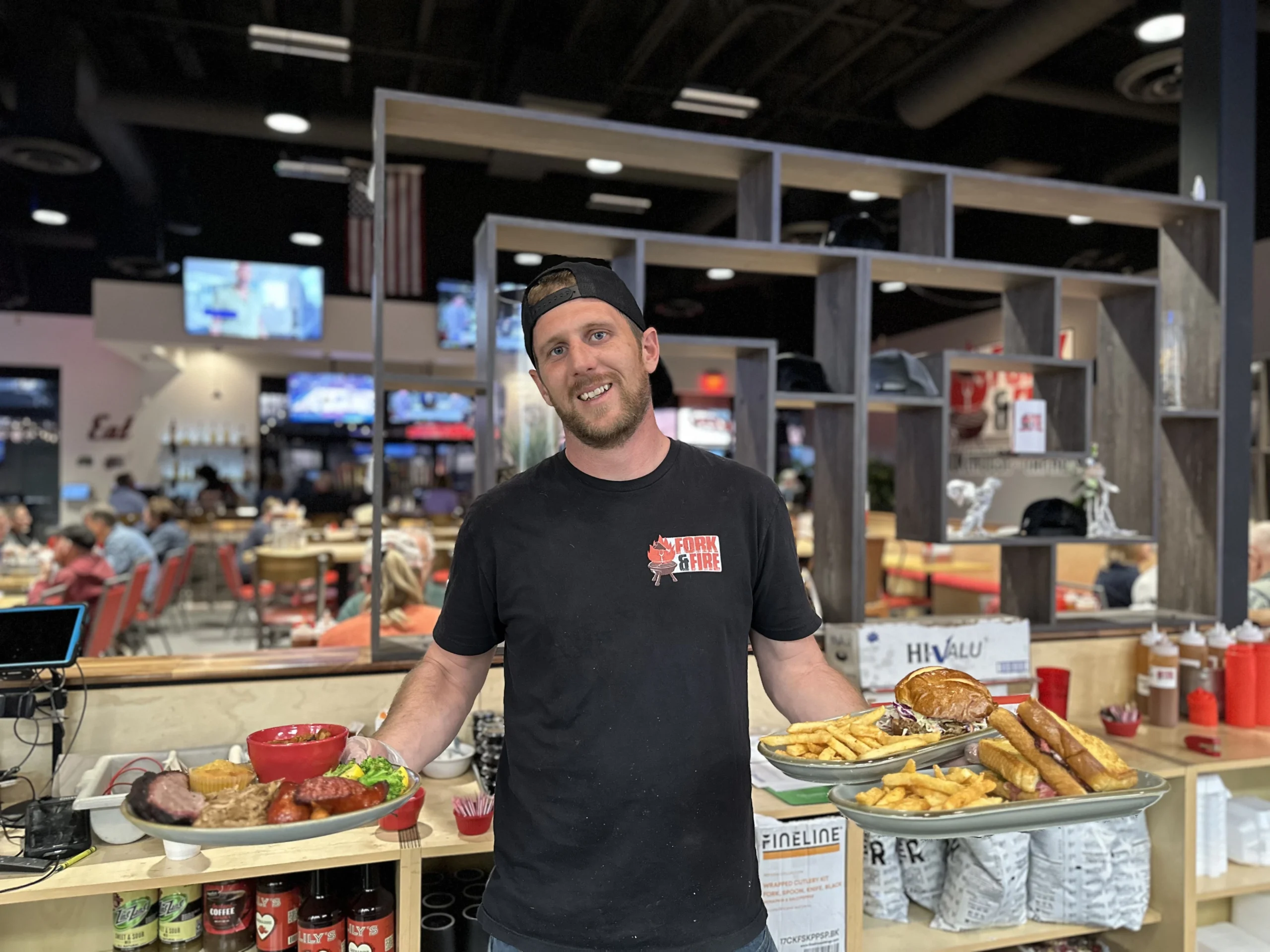 Employee at Fork & Fire holding three dishes.